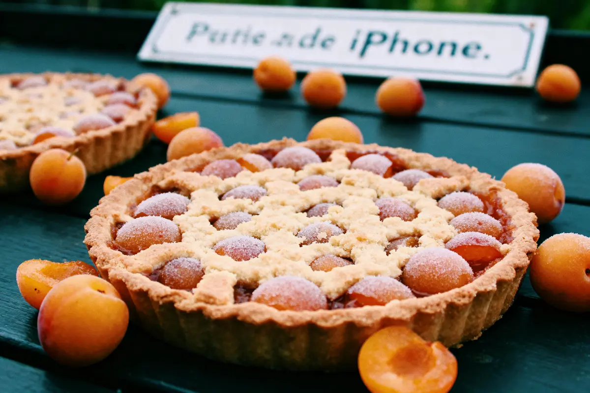 Tarte aux fruits dorés sur table, panneau flou "Photo de iPhone" en arrière-plan.