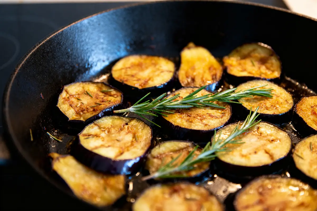 Tranches d'aubergines grillées dans une poelée d'aubergines au romarin sur une poêle noire