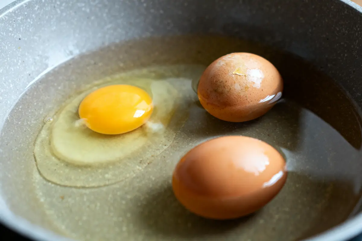Deux œufs entiers et un œuf cassé dans une poêle pour tester les oeufs