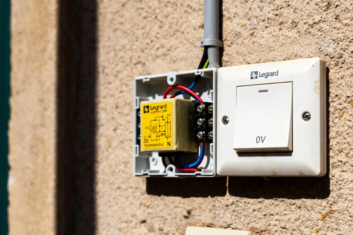Boîtier ouvert illustrant le schéma de branchement sonnette Legrand 230V avec fils électriques apparents